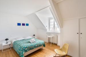 a white bedroom with a bed and a chair at La Villa Souhaitier in Saint Malo