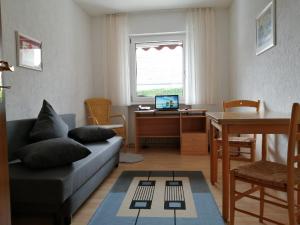 ein Wohnzimmer mit einem Sofa und einem Schreibtisch mit einem Laptop in der Unterkunft Gästehaus Diemer in Margetshöchheim