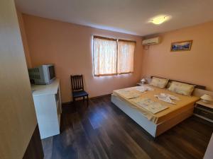 Habitación pequeña con cama y escritorio. en Къща за гости Яневи en Ravda