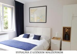 a white bed with blue pillows in a bedroom at Bulwar Gdynia in Gdynia