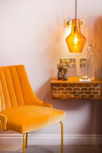 una silla naranja junto a una mesa con una lámpara en The Queen's Inn, en Hawkhurst