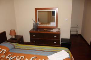 a bedroom with a bed and a dresser with a mirror at Bella Italia Bem Estar Dona Adelina in Ponta Garça