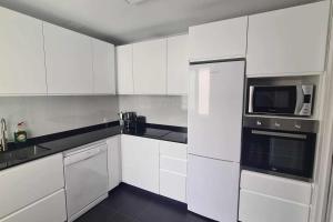 a white kitchen with white cabinets and a microwave at Apartamento la Fortaleza in San Vicente de la Barquera