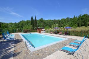 a swimming pool with blue chairs and umbrellas at Casale Tigli in Capolona
