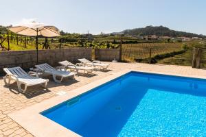 a blue swimming pool with chairs and an umbrella at Idyllic Villa in Fornos + Pool! in Fornos