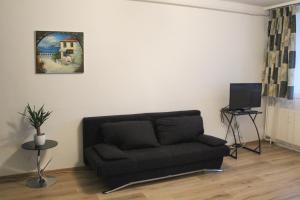 a living room with a couch and a tv at Sunset-view Apartment in Debrecen