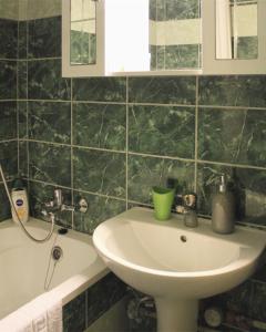 a green tiled bathroom with a sink and a tub at Sunset-view Apartment in Debrecen