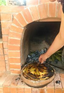 una persona sosteniendo una pizza en un horno de ladrillo en Agro Guest House Tsiskari in Machakhela en Khelvach'auri