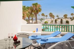 een terras met stoelen en een tafel en een zwembad bij Lanzahost Apartamento LARIMAR in Costa Teguise