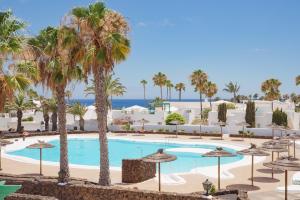 een afbeelding van een zwembad met palmbomen en de oceaan bij Lanzahost Apartamento LARIMAR in Costa Teguise