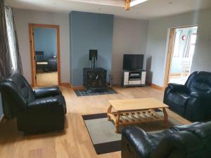 a living room with black leather furniture and a coffee table at Murphys Irish Farmhouse in Tralee