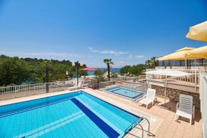 a pool with chairs and umbrellas at a resort at Hotel Zorna Plava Laguna in Poreč