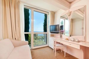 a living room with a desk and a large window at Hotel Zorna Plava Laguna in Poreč