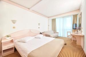 a hotel room with a large bed and a chair at Hotel Zorna Plava Laguna in Poreč