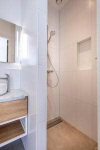 uma casa de banho branca com um chuveiro e um lavatório. em Singel 9 em Domburg