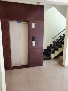 a hallway with a white door in a building with stairs at Royal Suvarna Comforts in Mysore