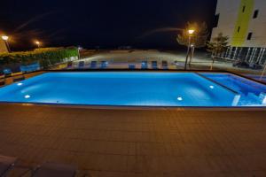 a large blue swimming pool at night at Jijo's Hotel in Mamaia