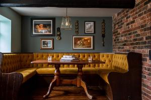 uma mesa num bar com um banco e uma parede de tijolos em The Filly Inn em Brockenhurst