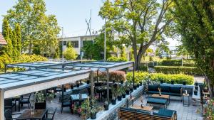 an outdoor patio with tables and chairs and potted plants at Hotel Tihany Átrium in Tihany