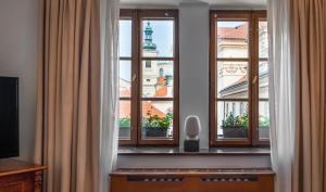 a room with three windows looking out at the city at Hotel Aurus by Adrez in Prague