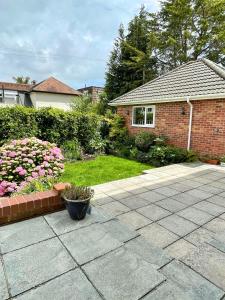 a house with a yard with flowers and a patio at Beautiful Large 4 bedroom House - 5 Minute Walk to the Best Beach! - Great Location - Garden - Parking - Fast WiFi - Smart TV - Newly decorated - sleeps up to 10! Close to Bournemouth & Poole & Sandbanks in Bournemouth