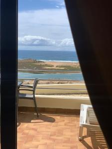 a chair sitting on a balcony looking out at the ocean at Auberge Oualidia Dream in Oualidia