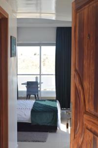 a bedroom with a bed and a window with a desk at Auberge Oualidia Dream in Oualidia