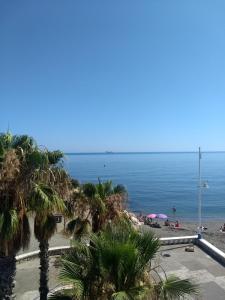 Blick auf einen Strand mit Palmen und das Meer in der Unterkunft Apartments-OILAN11 - Estudios en primera línea de playa PEDREGALEJO in Málaga