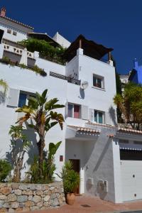 a white building with a palm tree in front of it at Casa Altos 76 in La Herradura