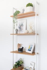 a white shelf with plants and pictures on it at Cove Suites Apartment in Iraklitsa