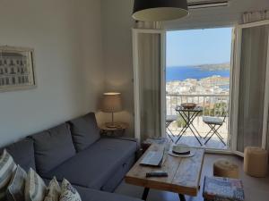 a living room with a blue couch and a large window at Plakes Luxury Apartments in Ermoupoli