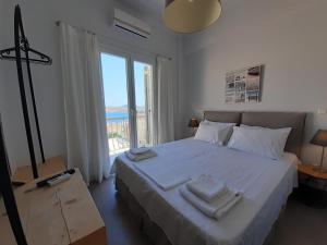 a bedroom with a large white bed with towels on it at Plakes Luxury Apartments in Ermoupoli