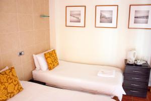 two beds in a room with pictures on the wall at Casa Don Juan in Benidorm