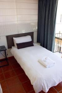 a bedroom with a white bed with a window at Casa Don Juan in Benidorm