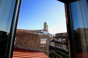 een uitzicht vanuit een raam van een gebouw met een klokkentoren bij D&S - Lapa 32 in Porto