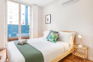 a white bedroom with a bed with a window at Oporto Palace Apartments in Porto