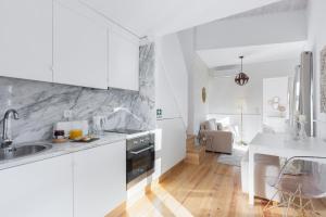 a white kitchen with a sink and a table at Loureiro Villas in Porto