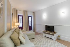a living room with a white couch and a tv at Loureiro Villas in Porto