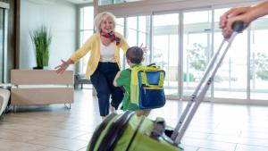 羅斯芒特的住宿－奧黑爾區假日酒店，一名年纪较大的妇女和一名带着行李走路的孩子