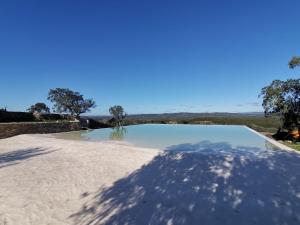 a swimming pool with a blue sky in the background at Chão da Velha - Casas de Campo in Nisa