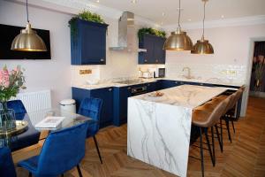 a kitchen with blue cabinets and a kitchen island with blue chairs at Sea Watch Seafront Holiday House in The Mumbles