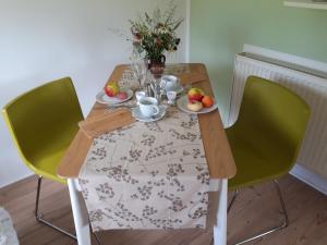 einem Holztisch mit grünen Stühlen und einem Tisch mit Obst darauf in der Unterkunft Villa Sonja in Kurort Altenberg
