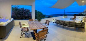 ein Wohnzimmer mit einem Tisch, Stühlen und einer Badewanne in der Unterkunft Exclusive 2 Bedroom Seafront Suite with jacuzzi in Zavala