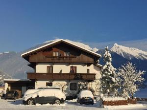 dos autos estacionados frente a una casa con nieve en Gästehaus Bliem, en Mayrhofen