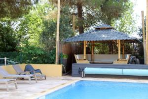 een zwembad met een prieel en stoelen naast een zwembad bij Résidence les Caraibes in Sérignan