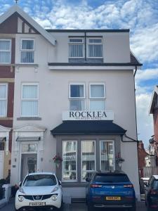 a white building with cars parked in front of it at Rocklea Hotel in Blackpool