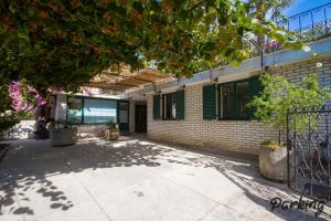 a building with green shuttered windows and a tree at Apartments Kolenc in Portorož