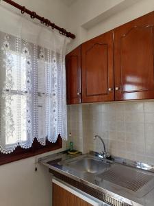 eine Küche mit Holzschränken, einem Waschbecken und einem Fenster in der Unterkunft KALLIOPIS STUDIO in Olympos