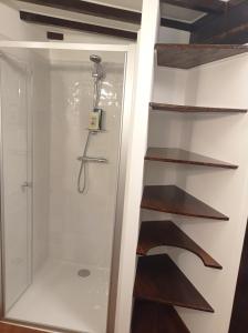 a shower in a bathroom with wooden shelves at Chez Fred et Cécile in Verdilly