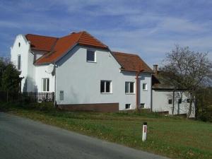 una casa blanca con techo rojo a un lado de la carretera en HIŠA VILMOŠ / HOUSE VILMOŠ en Prosenjakovci